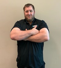 a man with his arms crossed in front of a wall